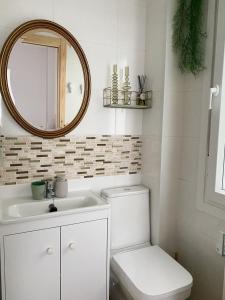 Un baño blanco con inodoro y espejo. en Apartamento C/ Concepción Arenal, en Ferrol