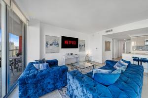 a living room with two blue couches and a kitchen at Beachwalk Resort #2102 - OCEAN VIEW WRAP AROUND BALCONY 3BD - 3BR CONDO No Resort and Parking Fees in Hallandale Beach