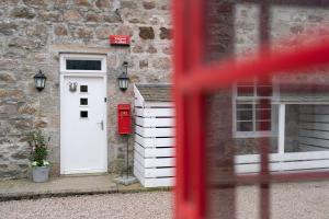 ein Haus mit einer weißen Tür und einem roten Briefkasten in der Unterkunft Ranch House Cottage 