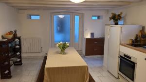 a kitchen with a table with a vase of flowers on it at Le Petit Lavoir - Maison Cosy à Mayet in Mayet