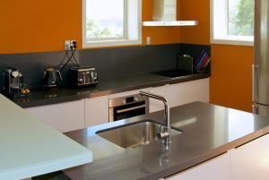 a kitchen with a stainless steel sink and orange walls at The Church at Fox in Fox Glacier