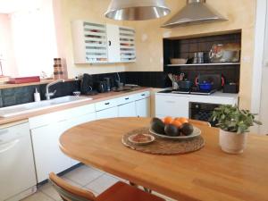 una cocina con una mesa de madera y un bol de fruta en Maison de famille, en Saint-Mars-dʼOutillé