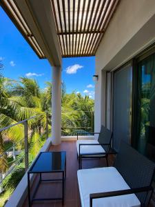a balcony with chairs and tables and a view of the ocean at Maia Suites Cozumel in Cozumel