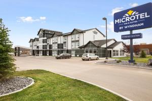 un gran edificio con coches estacionados en un estacionamiento en Microtel Inn & Suites by Wyndham Blackfalds, en Blackfalds