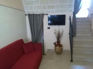 sala de estar con sofá rojo y TV en Dimora San Biagio, en Veglie