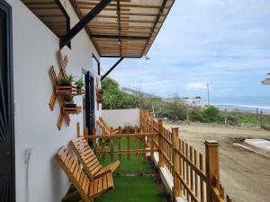 a porch with wooden chairs and a view of the ocean at SUITES BRISAMAR PLAYA SANTA MARIANITA Manta in Manta