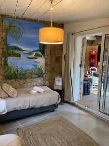 a bedroom with a bed and a painting on the wall at Maranatha, front de mer avec plage in Porto-Vecchio