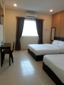 a hotel room with two beds and a desk and a window at Alor Villa in Melaka