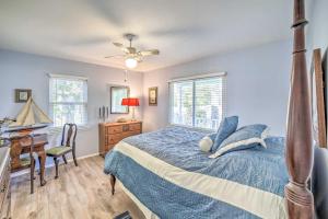 a bedroom with a bed with a blue comforter and a desk at Oak Island Home with Yard Less Than 1 Mi to the Beach! in Oak Island