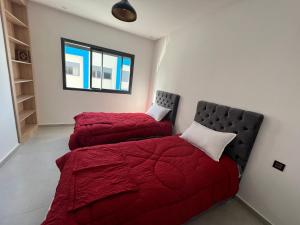 two beds in a bedroom with red comforter at Appartement familial Soleil et Mer à 150m de la Plage de Mehdia in Plage de Mehdia