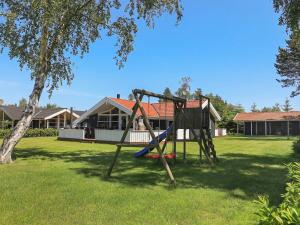 a swing set in a yard with a house at Holiday Home Sølvgranvej in Marielyst