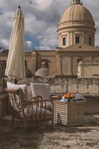 un patio con una silla, una sombrilla y una mesa en Palazzo Trigona Suites, en Noto