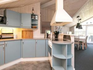 a kitchen with blue cabinets and a dining room at Holiday Home Sølvgranvej in Marielyst