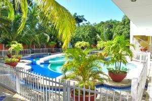 a resort swimming pool with palm trees and a white fence at Hotel Campestre Villa Ocha in Valledupar