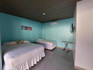 two beds in a room with blue walls at Hotel Casa Carlota Tamarindo in Tamarindo