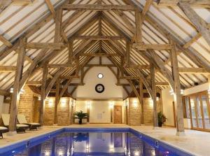 a large swimming pool in a building with wooden ceilings at Lakeview Lodge in Wisbech