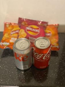 two cans of soda sitting on a counter with snacks at Cosy Studio West Hampstead in London
