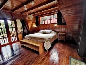 ein Schlafzimmer mit einem Bett in einer Holzhütte in der Unterkunft Oxablues Home Lodge in Oxapampa