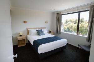 Wanaka Top 10 Holiday Park في واناكا: غرفة نوم بسرير ونافذة كبيرة