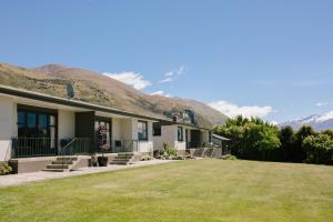 una casa con césped frente a una montaña en Wanaka Top 10 Holiday Park en Wanaka