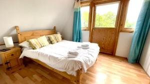 Spacious Primrose Lodge for 6 with Hot Tub at a Spa Resort في Chudleigh: غرفة نوم بسرير وملاءات بيضاء وستائر زرقاء