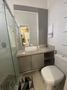 a bathroom with a toilet and a sink and a mirror at Apto 3 Suítes para famílias com vista para o mar in Itapema