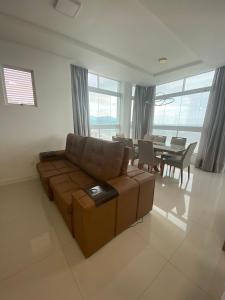 a living room with a couch and a dining room at Apto 3 Suítes para famílias com vista para o mar in Itapema