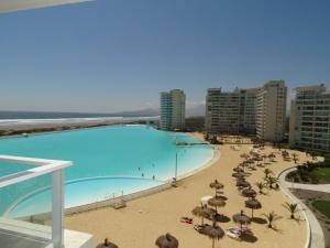 una gran piscina con sombrillas y gente en la playa en Laguna del Mar Suites, en La Serena