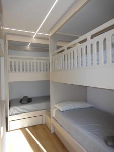 2 beliches brancos num quarto com pisos em madeira em Somo. A pie de playa em Somo