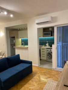 sala de estar con sofá azul y cocina en Julia's House en Buenos Aires