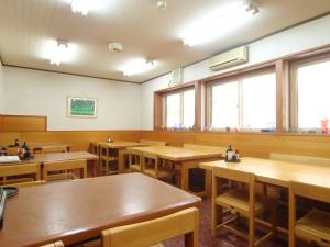 an empty restaurant with wooden tables and windows at Hakuraiso in Matsumoto