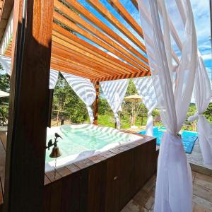 a view of a swimming pool with a wooden pergola at Pousada Aconchego in Pirenópolis