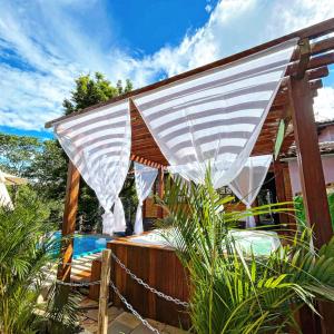 皮雷諾波利斯的住宿－Pousada Aconchego，游泳池旁的热水浴池上方的白色天篷