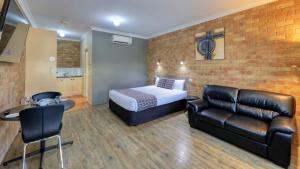 Habitación de hotel con cama y sofá de cuero en Bridges on Meninya Motel & Apartments, en Moama