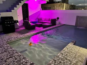 a swimming pool in a house with purple lighting at Satisfaction in San Juan