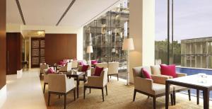 un comedor con mesas, sillas y ventanas en The Oberoi Gurgaon, en Gurgaon