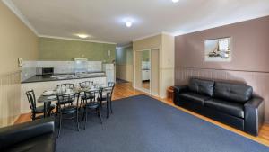 a living room with a table and a black leather couch at Bridges on Meninya Motel & Apartments in Moama