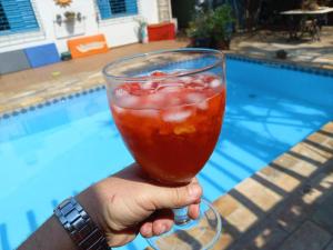 a person holding a drink in front of a pool at Alpha Hospedaria & Hostel in Londrina