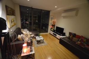 a living room with a black couch and a television at Riverside Resort Apartment in Melbourne