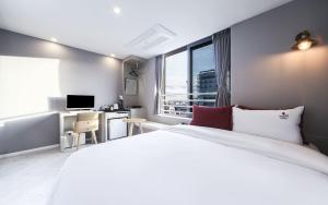 Maron Hotel Nampo في بوسان: غرفة نوم مع سرير أبيض كبير ومكتب