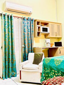 um quarto com uma cama, uma cadeira e cortinas em RNM The Clubhouse, Grenada em Mount Nesbit