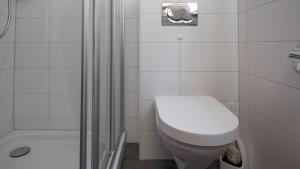 ein weißes Bad mit einem WC und einer Dusche in der Unterkunft Toggi OG in Bettmeralp