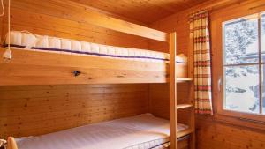 2 Etagenbetten in einer Holzhütte mit einem Fenster in der Unterkunft Toggi OG in Bettmeralp
