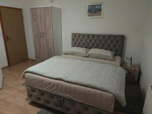 Schlafzimmer mit einem großen Bett mit einem Kopfteil aus Leder in der Unterkunft Apratmani Ivić in Kupres