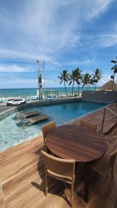 una mesa de madera y sillas junto a la playa en Loft de Alto Padrão na Orla de Maceió, en Maceió