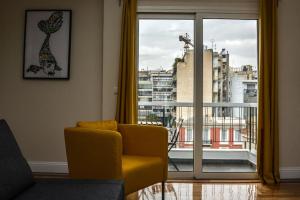 a living room with a yellow couch and a large window at The Parthenon Terrace ReNoVaTeD with a view ! in Athens