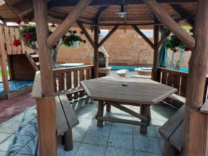 een houten pergola met een tafel op een patio bij Sissy Vendégház in Mórahalom