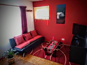 a living room with a black couch and a red wall at Departamento Urbano in San Carlos de Bariloche