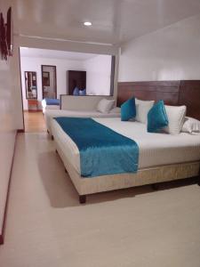 a bedroom with two beds with blue pillows at Hotel Casa Lamay in Bogotá