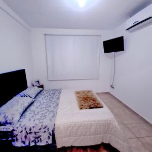 Habitación blanca con cama y TV en departamentos corrientes en Corrientes